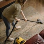 High-angle view of a woman vacuuming a patterned carpet in a stylish living room.